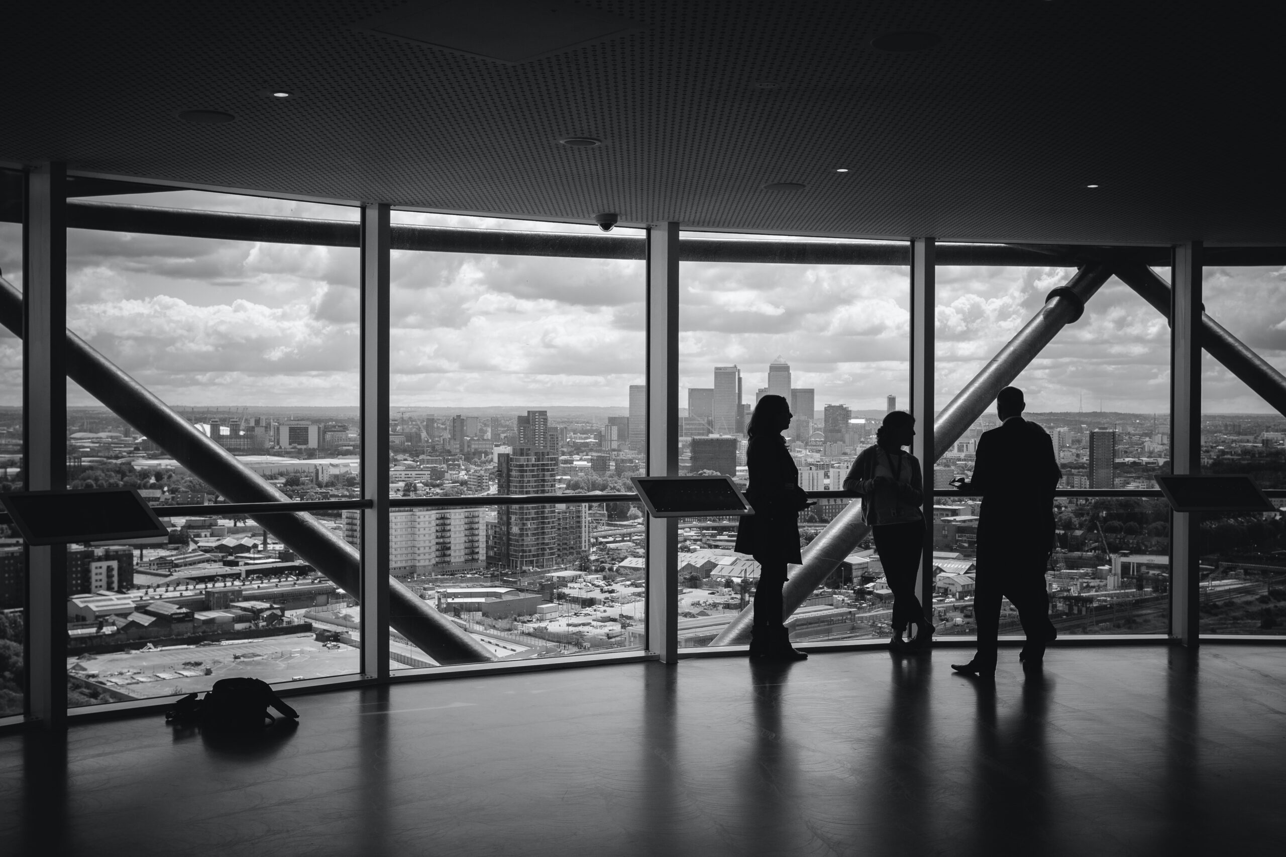 silhouette of 3 people against skyscraper window above city